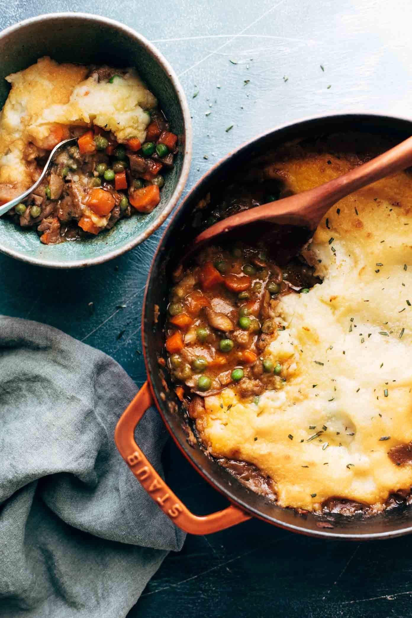 White hand scooping vegetarian shepherd's pie with a wooden spoon.