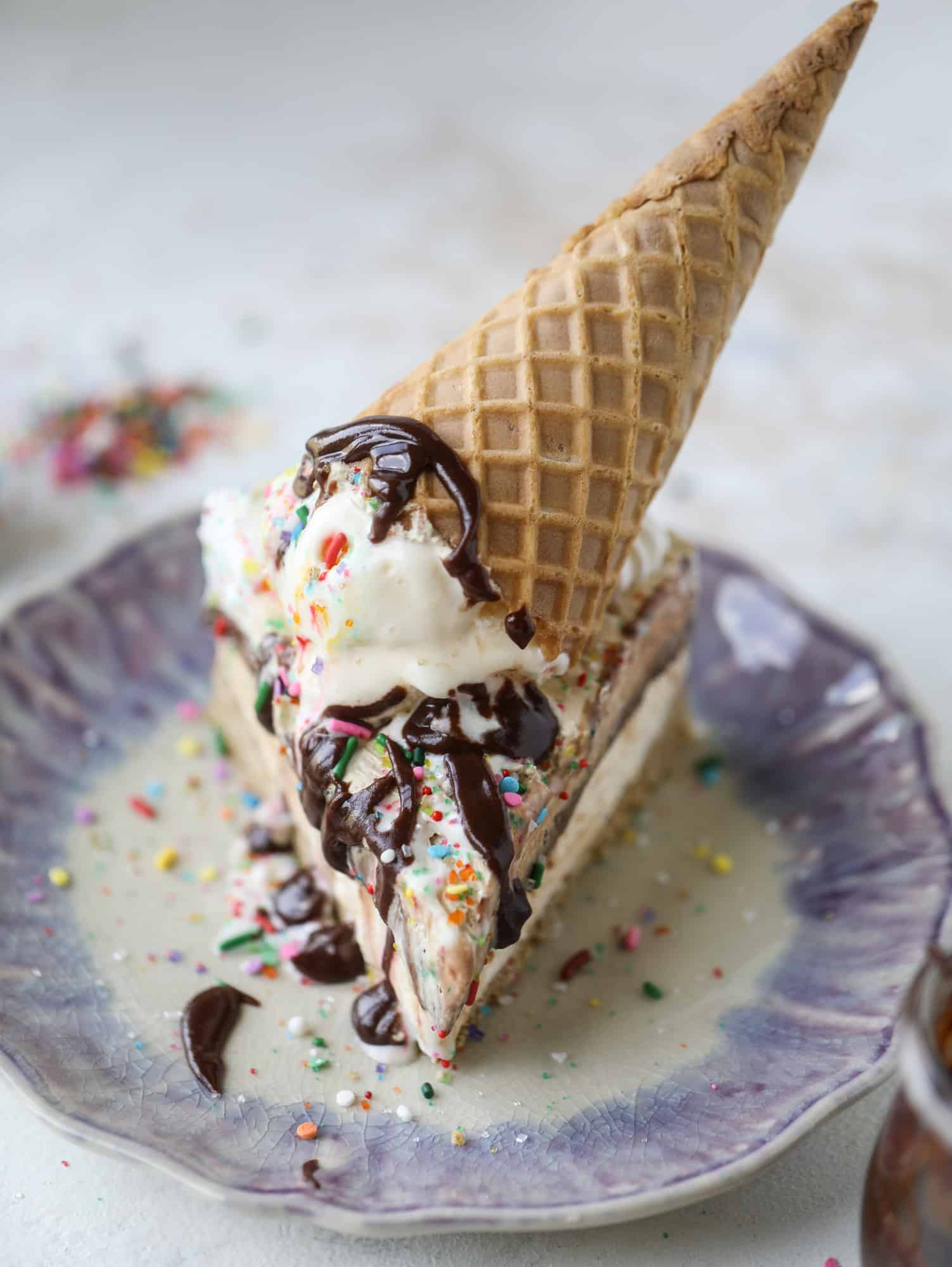 This peanut butter fudge ice cream cake is absolutely insane and perfect for summer! A sweet and savory pretzel crust, vanilla ice cream, homemade hot fudge and a peanut butter whipped cream layer take it to the next LEVEL. Delicious! I howsweeteats.com #icecream #cake #peanutbutter #chocolate #pretzel
