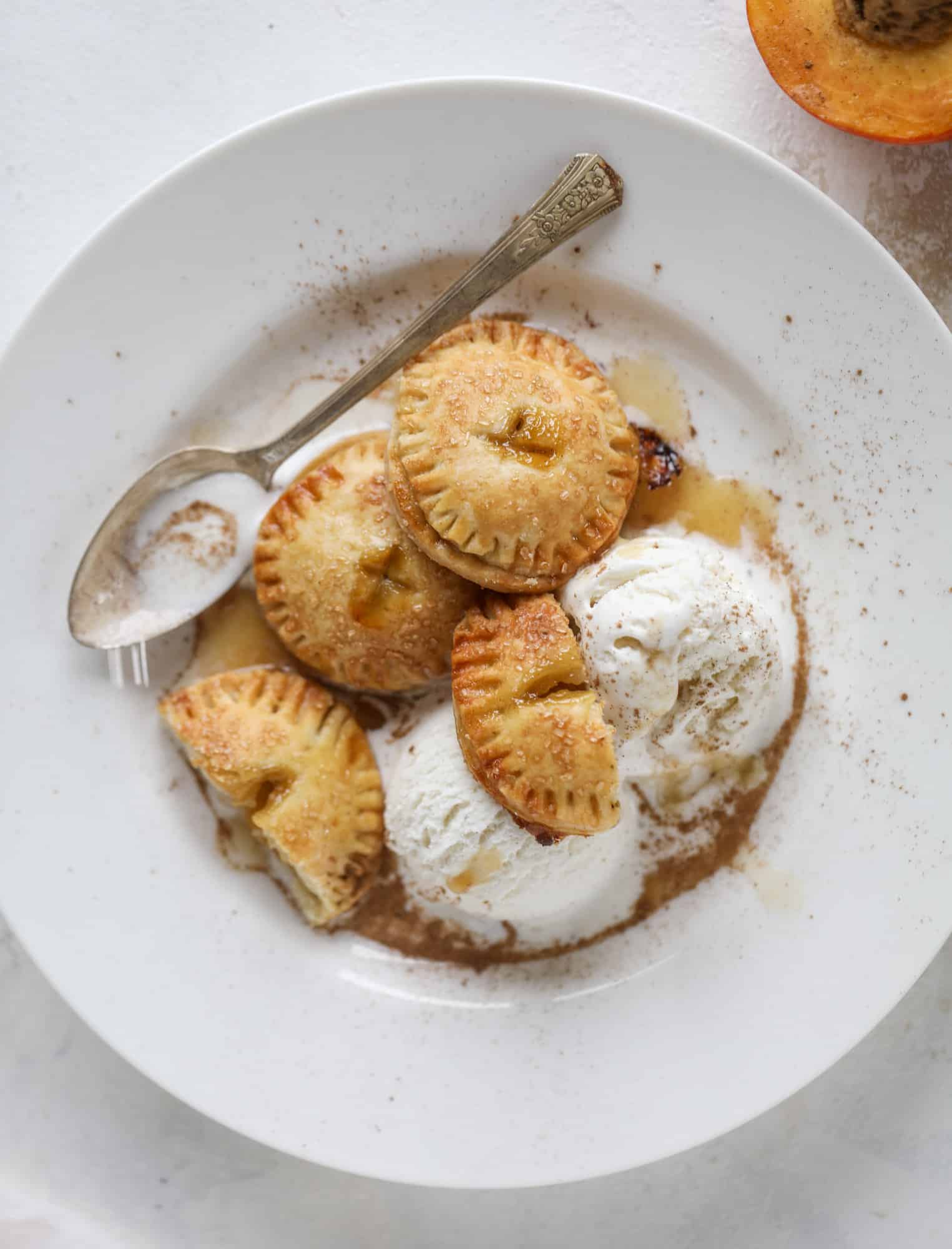 These little peach hand pies are super easy to make and oh-so delicious for summer! A warm and syrupy homemade peach filling made with brown sugar and bourbon, stuck inside a flakey all-butter crust and sprinkled with coarse sugar. SO GOOD. I howsweeteats.com #peach #hand #pies #mini #dessert #summer