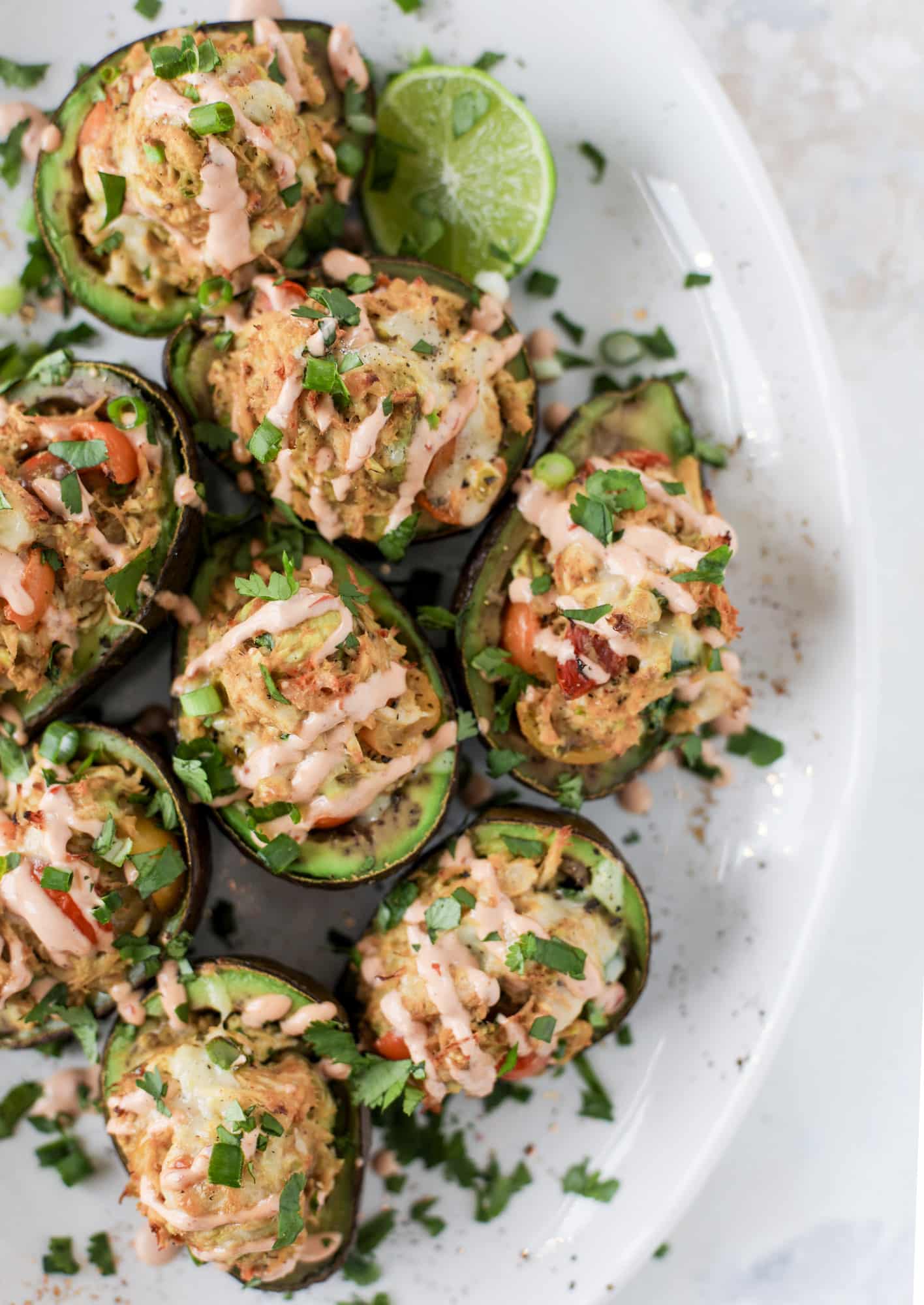 These baked avocados are stuffed with a cheesy chicken mixture and drizzled with sriracha yogurt sauce! Super delicious and an easy weeknight meal. I howsweeteats.com #baked #avocados