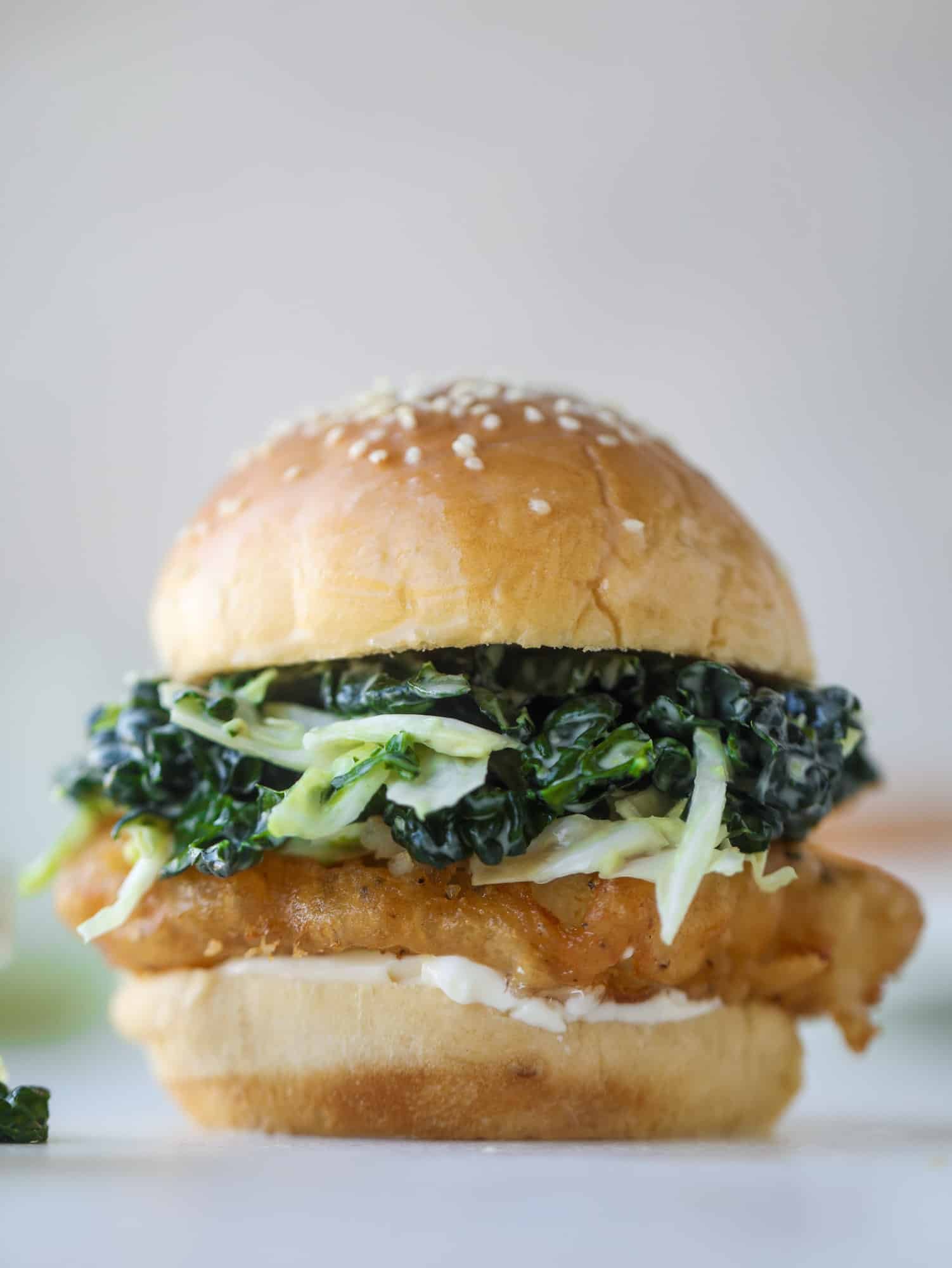 A light and crispy fish sandwich made with a simple beer batter and topped with a hearty, creamy kale cole slaw. Loaded with flavor! I howsweeteats.com #crispyfish #sandwich