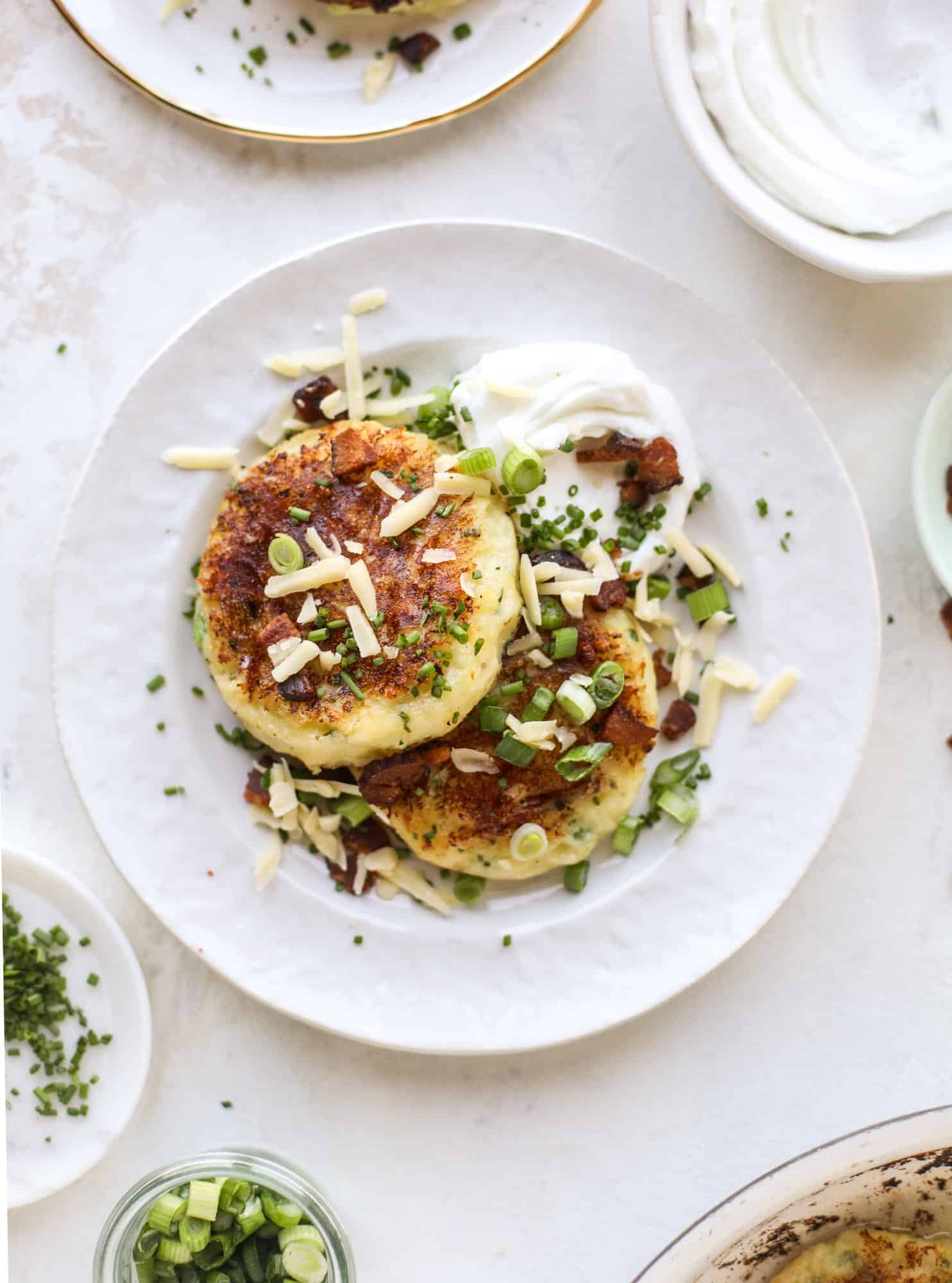 Loaded mashed potato pancakes are the perfect comfort food or side dish to a hearty meat. Crispy mashed potatoes with aged cheddar. Delicious! I howsweeteats.com #mashedpotato #pancakes