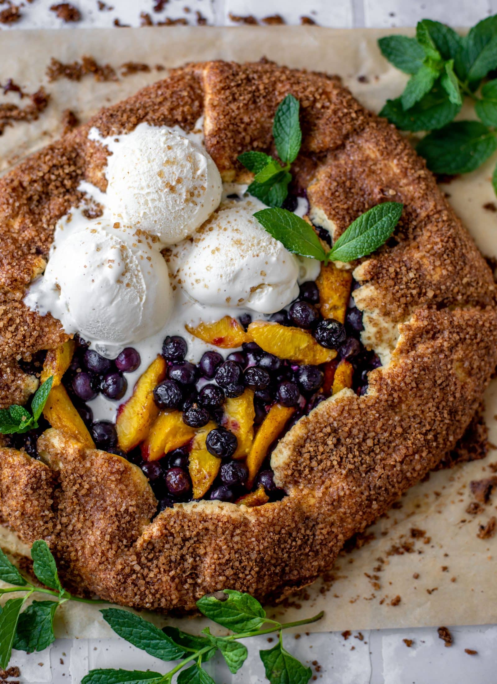 blueberry peach galette with cinnamon sugar galette topped with ice cream and fresh mint