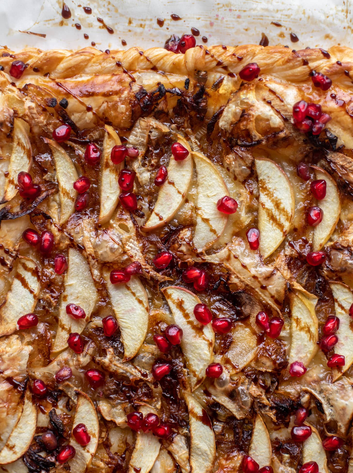 This apple brie tart starts with caramelized onions and puff pastry. It's topped with pomegranate molasses and juicy arils for an extra pop!