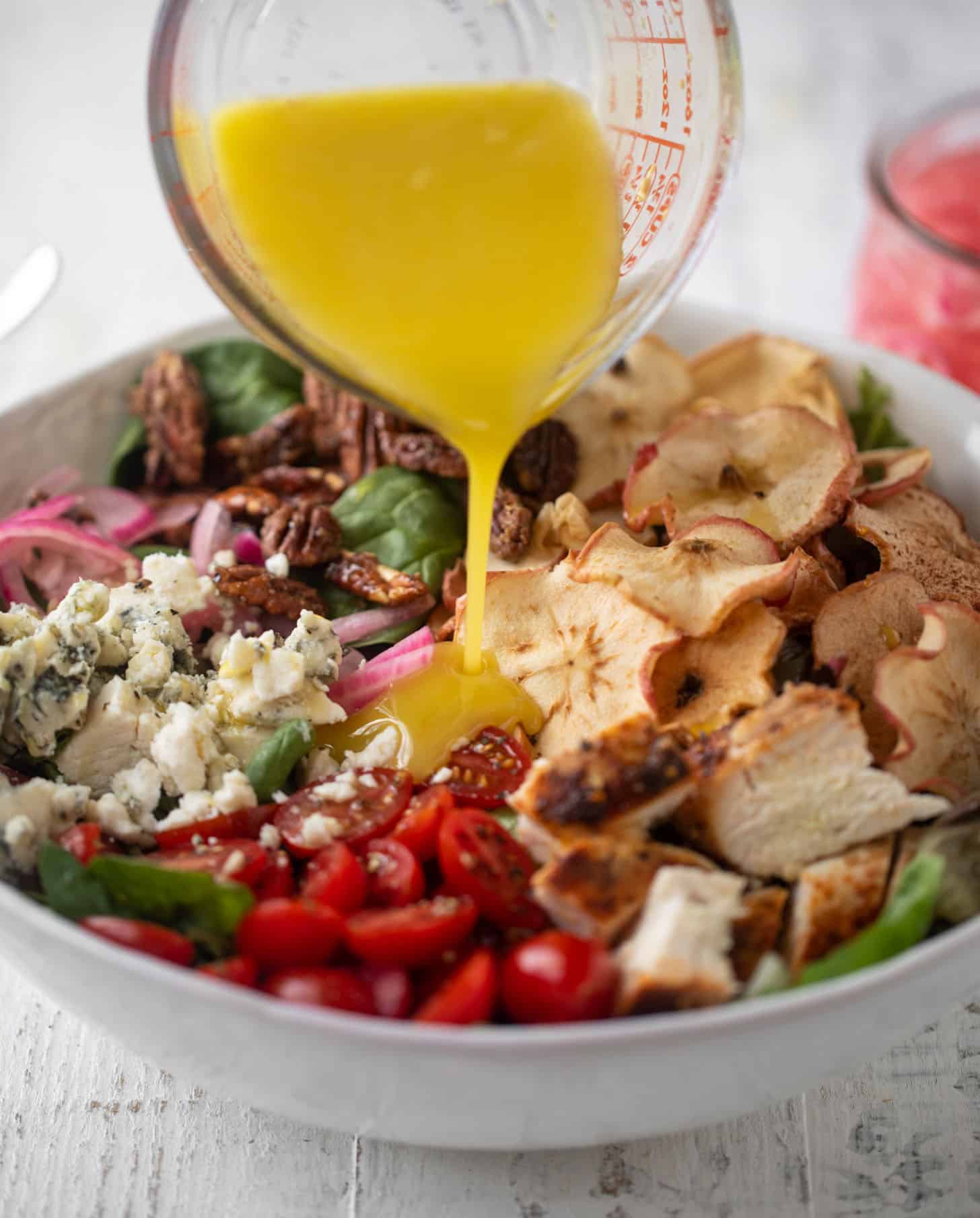 pouring champagne vinaigrette on fuji apple chicken salad 