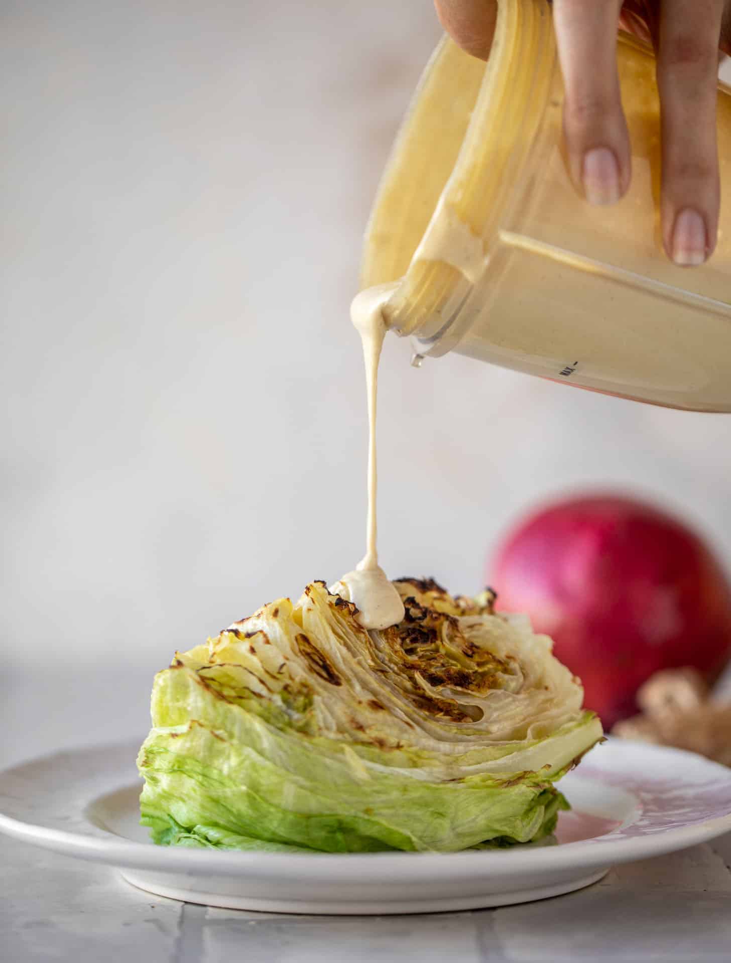 drizzling tahini ginger dressing on wedge