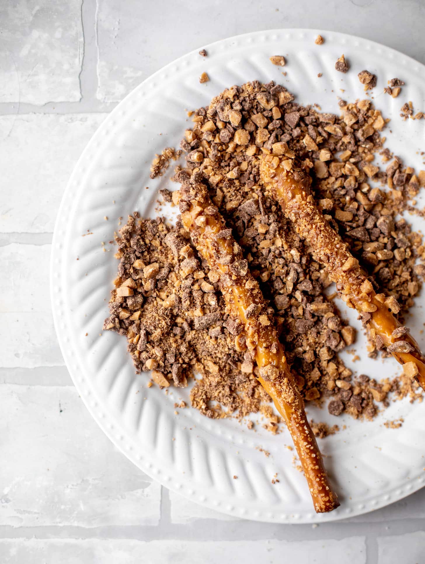 rolling caramel pretzels in toffee chips