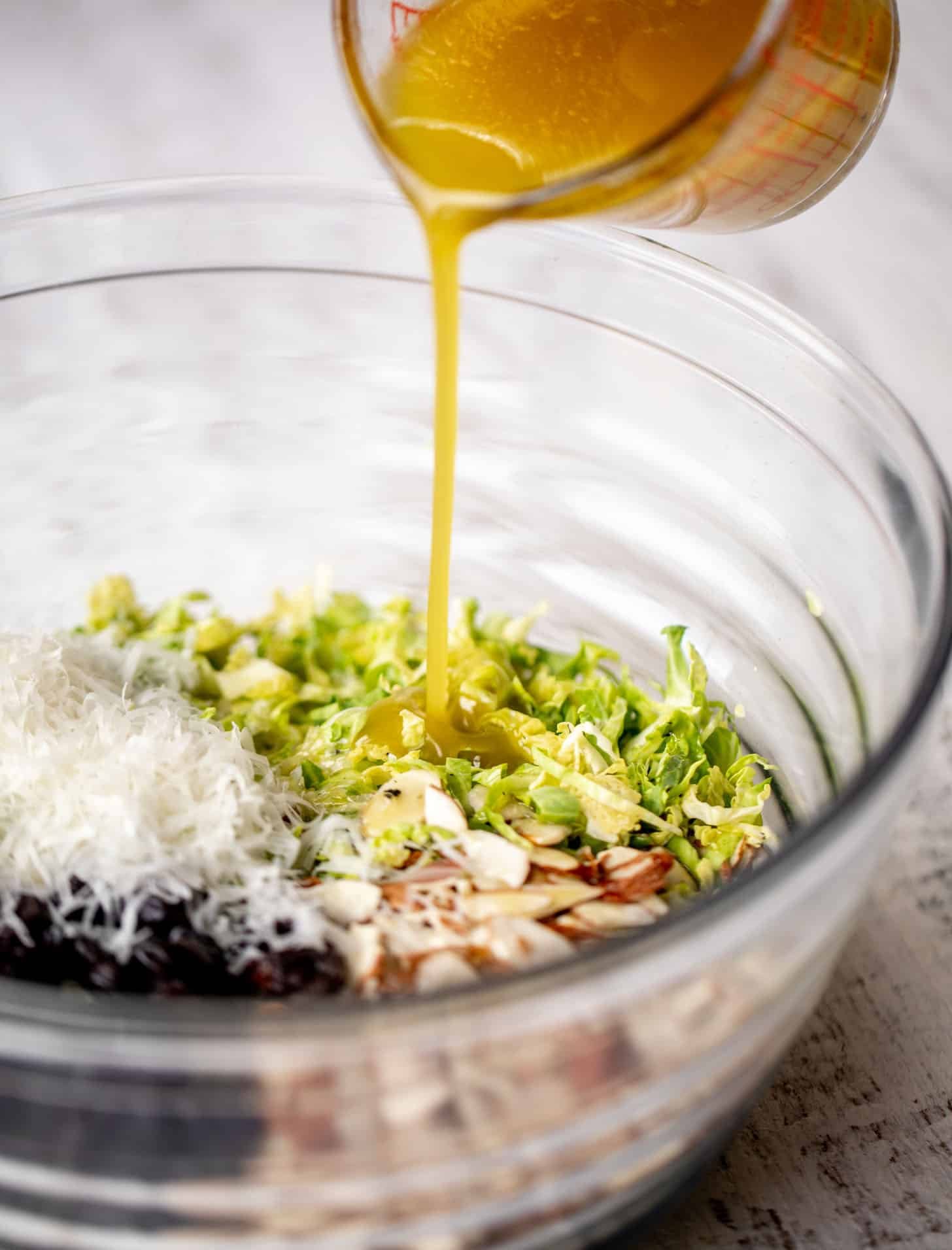 pouring dressing on brussels sprouts slaw