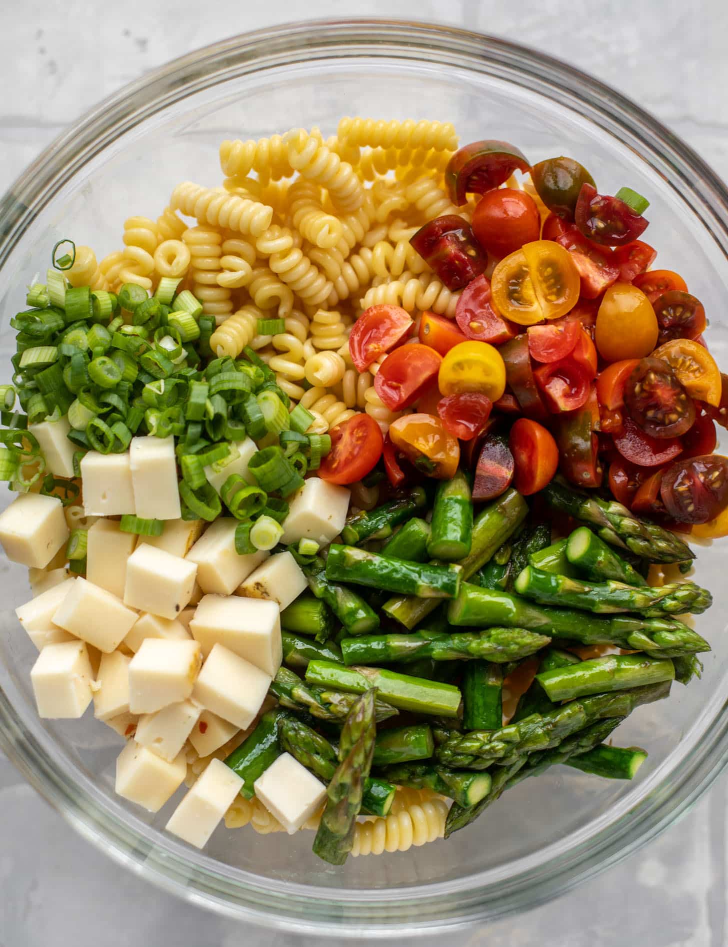 pasta, scallions, tomatoes, asparagus, cheddar in a bowl