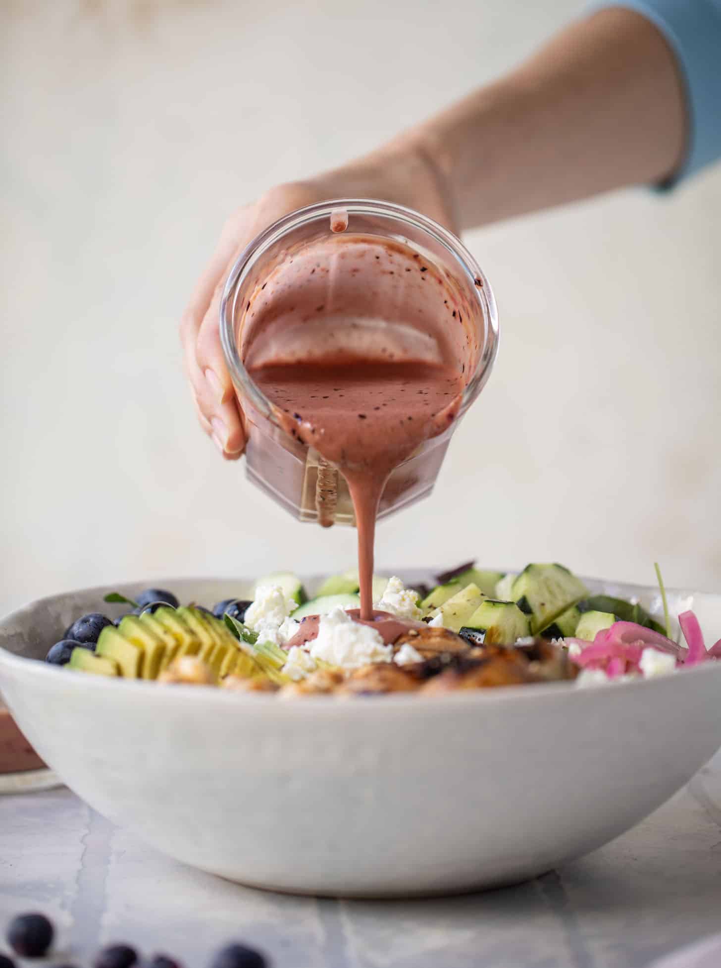 pouring blueberry vinaigrette on salad