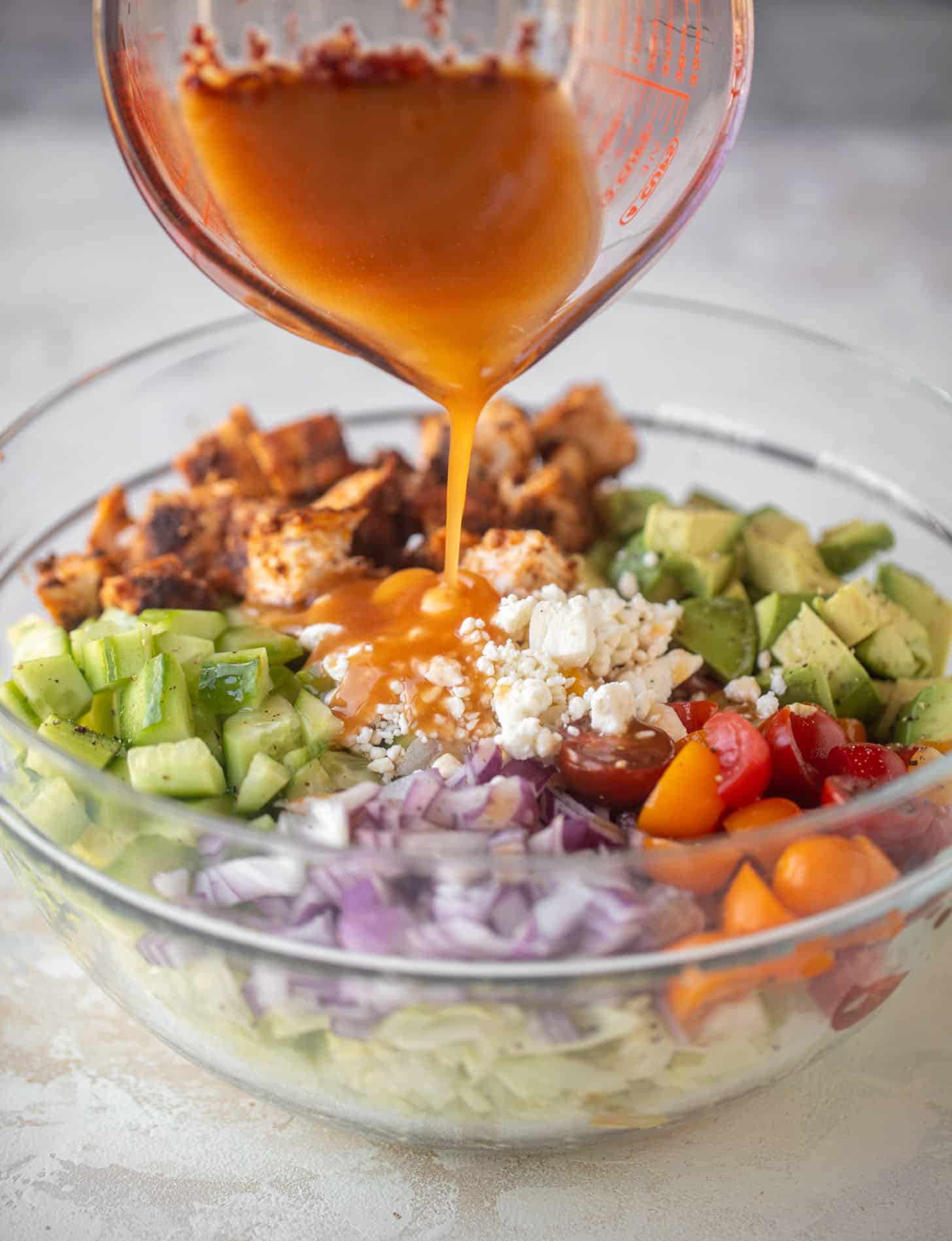 pouring dressing on blackened chicken chopped salad