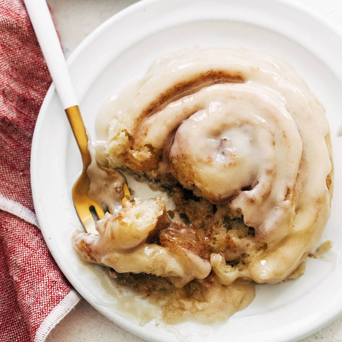 Cinnamon roll on a plate with a fork.